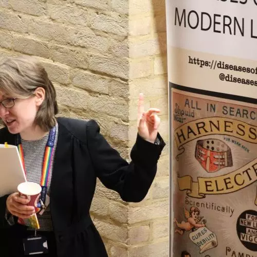 Dr Catherine Charlwood stands in front of the Diseases of Modern Life Banner